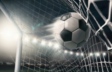Soccer ball hitting the net scoring a goal in a stadium at night