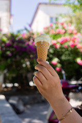 Ice cream cone in the hand of a woman on a background of flowers