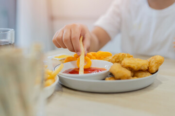 Boy' hand with French fries and nuggets on a white plate. Fast food for kids.