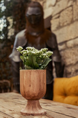 Bouquet of flowers in wooden vase on wooden table angainst medieval knight armor 