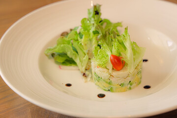 Gourmet Salad Presentation: A meticulously plated salad arrangement, featuring a vibrant mix of crisp greens, ripe avocado, and fresh cherry tomato, showcasing culinary artistry on a pristine plate. 