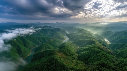 Aerial View of Lush Green Mountains Under Dramatic Cloudy Sky with Sunlight Rays