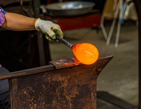 A glassblower's hands shaping molten glass. A dramatic concept of heat, fire, and artisanal craft