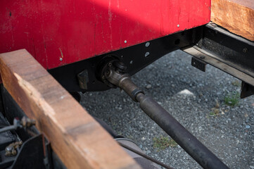 A detailed, close-up shot of the driveshaft and cardan joint on the undercarriage of a classic AA or BB truck with a wooden chassis.
