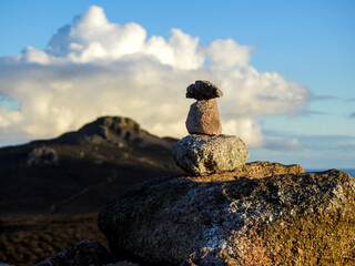 Stacked Rocks on Mountainous Terrain with Cloudy Sky