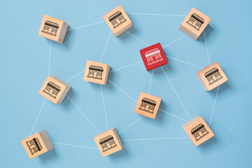 Franchise and business growth concept. Wooden cubes with store icons linked to each other with lines.