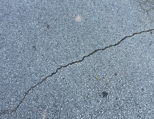 Cracked asphalt road surface with visible fracture line detail