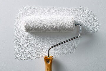 Fototapeta premium Close-up of a paint roller spreading a smooth coat of fresh paint on a wall, texture of wet paint clearly visible, set in a clean and minimalistic environment.