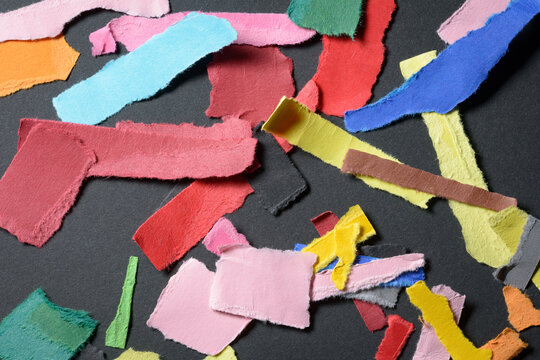 Stack or heap of colorful scraps, stripes or snippets of paper on dark background