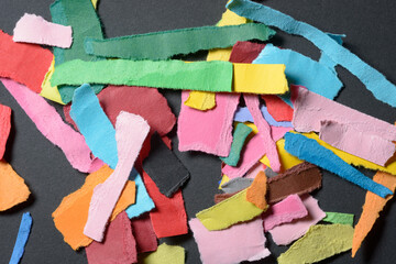 Stack or heap of colorful scraps, stripes or snippets of paper on dark background