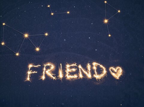 Sparkler writing of the word "FRIEND" with heart under stars  