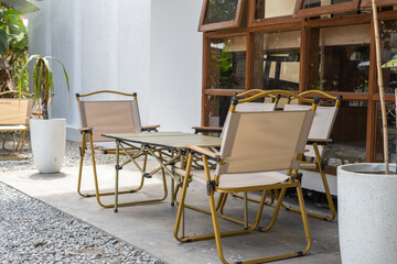 Outdoor café setting with foldable chairs and table arranged on gravel and concrete floor near...