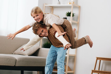 Authentic play scene shows a couple in a cozy home, sharing a joyful moment as one lifts the other in a playful piggyback pose, capturing genuine emotion and household charm.