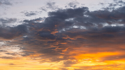 Obraz premium Fiery sunset sky with glowing orange light beneath dark dramatic clouds, captured in the evening to show nature’s contrast and beauty.