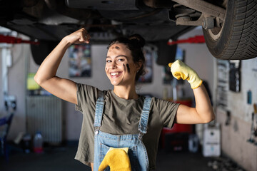A cheerful mechanic smiles proudly while showing off her strength amidst a workshop, embodying hard...