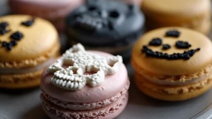 Colorful Halloween macarons, decorated with spooky skulls and playful jack-o'-lantern faces, evoke a festive and eerie vibe for a themed celebration