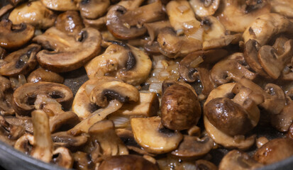 sliced mushrooms and onions sizzling in a hot pan