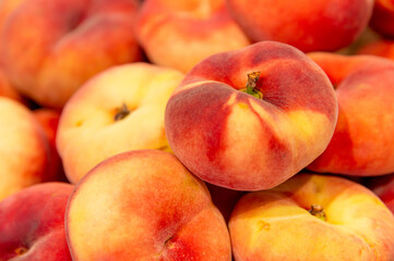 An arrangement of ripe, juicy peaches, yellow, and burgundy flowers. A close-up of organic food products