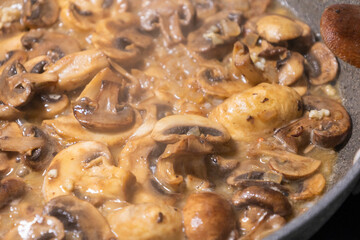 creamy mushroom sauce simmering in a pan with sautéed mushrooms and onions