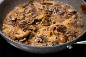 creamy mushroom sauce simmering in a pan with sautéed mushrooms and onions