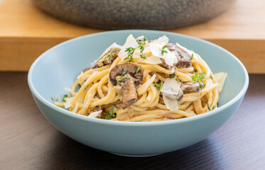 creamy pasta dish topped with savory mushroom sauce, grated parmesan, and fresh thyme, served in a blue bowl