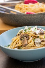 creamy pasta dish topped with savory mushroom sauce, grated parmesan, and fresh thyme, served in a blue bowl