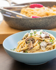 creamy pasta dish topped with savory mushroom sauce, grated parmesan, and fresh thyme, served in a blue bowl
