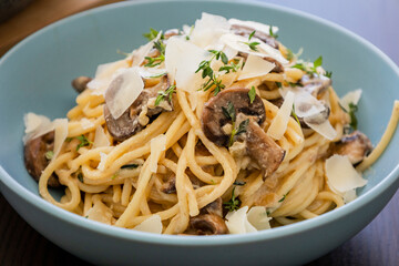 creamy pasta dish topped with savory mushroom sauce, grated parmesan, and fresh thyme, served in a blue bowl