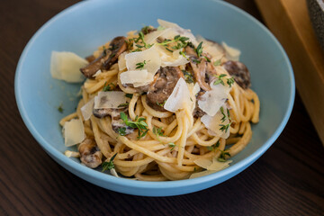 creamy pasta dish topped with savory mushroom sauce, grated parmesan, and fresh thyme, served in a blue bowl