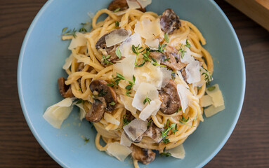 creamy pasta dish topped with savory mushroom sauce, grated parmesan, and fresh thyme, served in a blue bowl