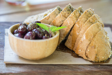 Mediterranean appetizer: olives and slices of bread with olive oil on wooden tray