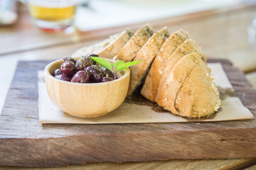 Mediterranean appetizer: olives and slices of bread with olive oil on wooden tray