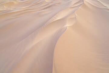 Obraz premium Aerial view of desert sand dunes with soft light creating shadows and textures in the sand