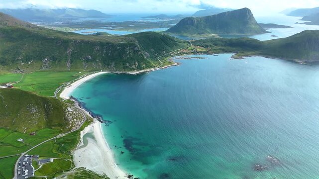 Experience the breathtaking scenery of Haukland Beach in Lofoten, Norway, where azure waters meet dramatic mountains. Explore this coastal paradise surrounded by lush landscapes and serene nature.