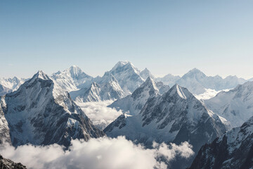 Photograph of a stunning mountain range with snow-capped peaks and fluffy white clouds below, under a clear blue sky.