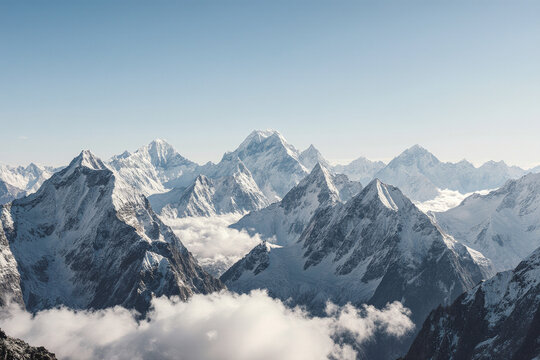 Photograph of a stunning mountain range with snow-capped peaks and fluffy white clouds below, under a clear blue sky. - Powered by Adobe