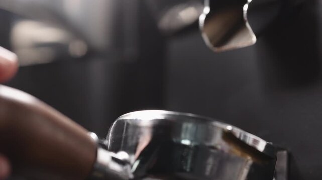 Slow motion freshly ground coffee falls into portafilter from grinder closeup