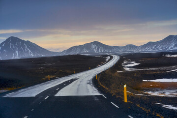 Road trip while travel after rainy time in Iceland with snow peak mountains view and colorful skyline.