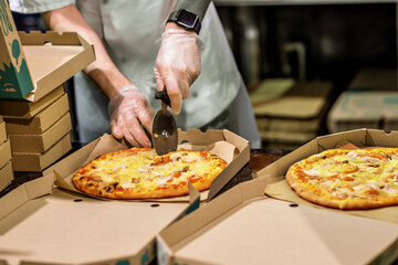 Cutting hot pizza in delivery box