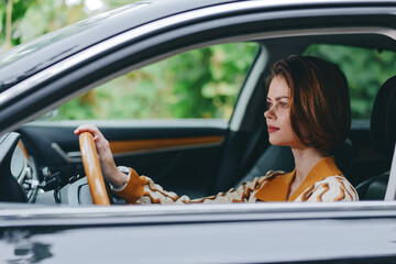 Naklejka premium A smiling woman driver sits comfortably in the car seat, hand on the steering wheel, ready for a journey and confident behind the wheel.