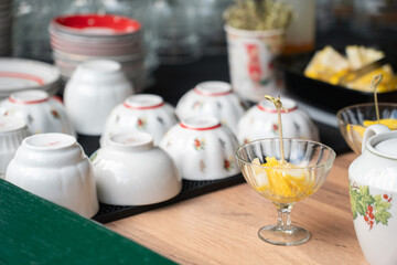 Traditional porcelain bowls with floral patterns displayed on a table alongside glass cups of fresh fruit