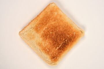A top-down close-up view of a perfectly toasted golden-brown slice of white bread on a white ceramic plate