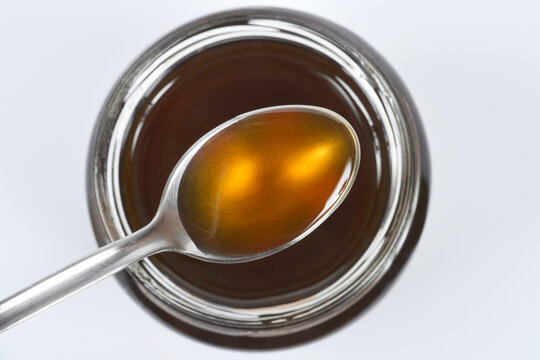 Spoonful of dark honeyA spoonful of dark honey hovering over an open jar of honey
