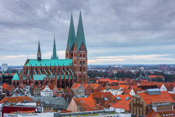 Obraz premium Aerial view of St. Mary's Church on the right side with the spires of Lubeck Cathedral in the background. The photo is a winter view of historical medieval part of Lubeck, Schleswig-Holstein, Germany.
