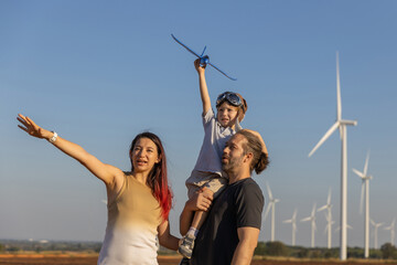 Family with son walking on field on wind farm. Happy Family and son playing at the Wind turbines generating electricity. Family time together.