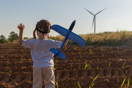 Boy Playing on field on wind farm. Happy Boy playing at the Wind turbines generating electricity. Family time together.
