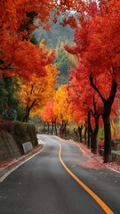 Obraz premium 鮮やかな紅葉に彩られた曲がりくねった道路。秋の風景や旅行案内に最適な自然景観