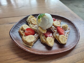 Delicious waffles topped with fresh fruit and ice cream, a delightful dessert