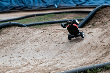 Radio-controlled car performing a jump on a dirt track