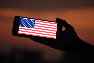 United States of America Flag Shown on Smartphone Screen Held in Hand at Sunset